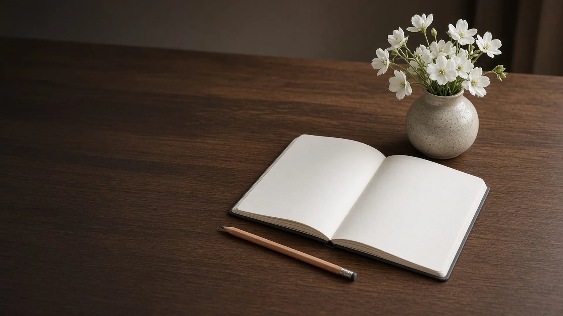 An open notebook beside white flowers on a desk