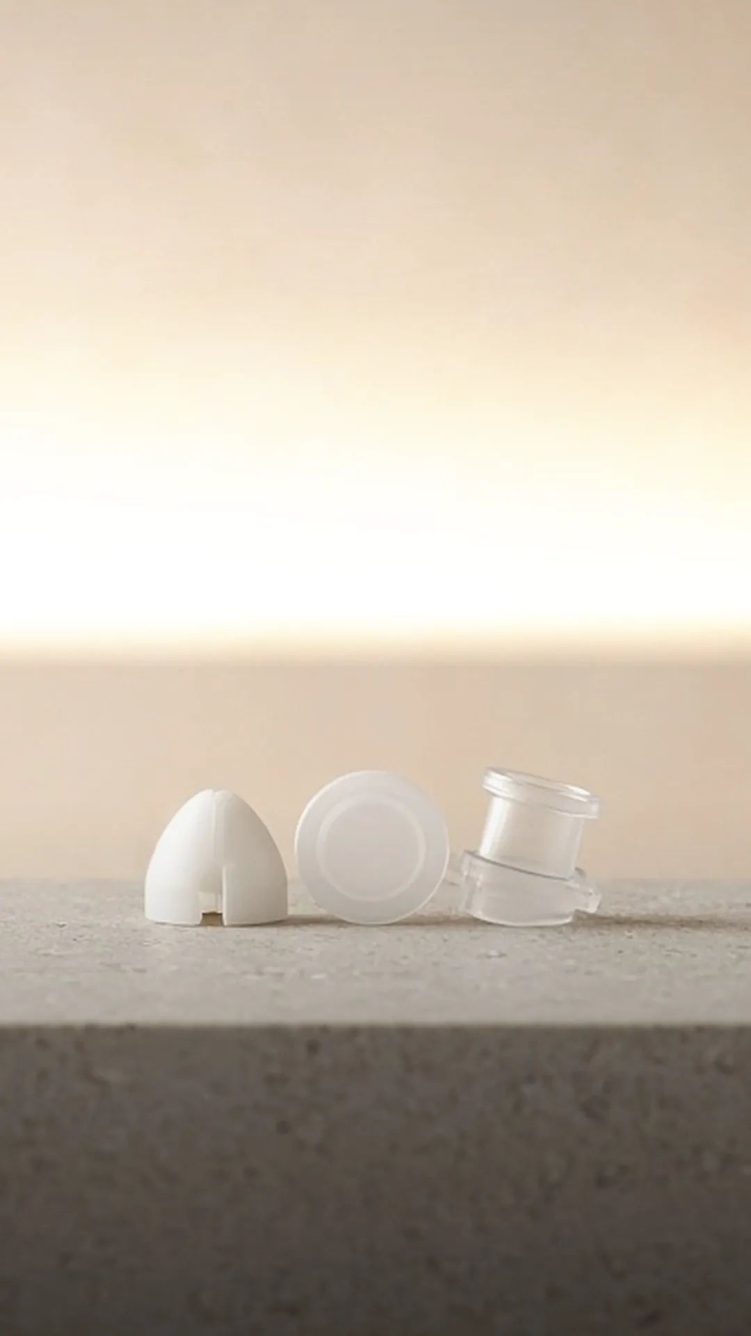 A white valve, a round membrane, and a clear connector on a pale stone ledge
