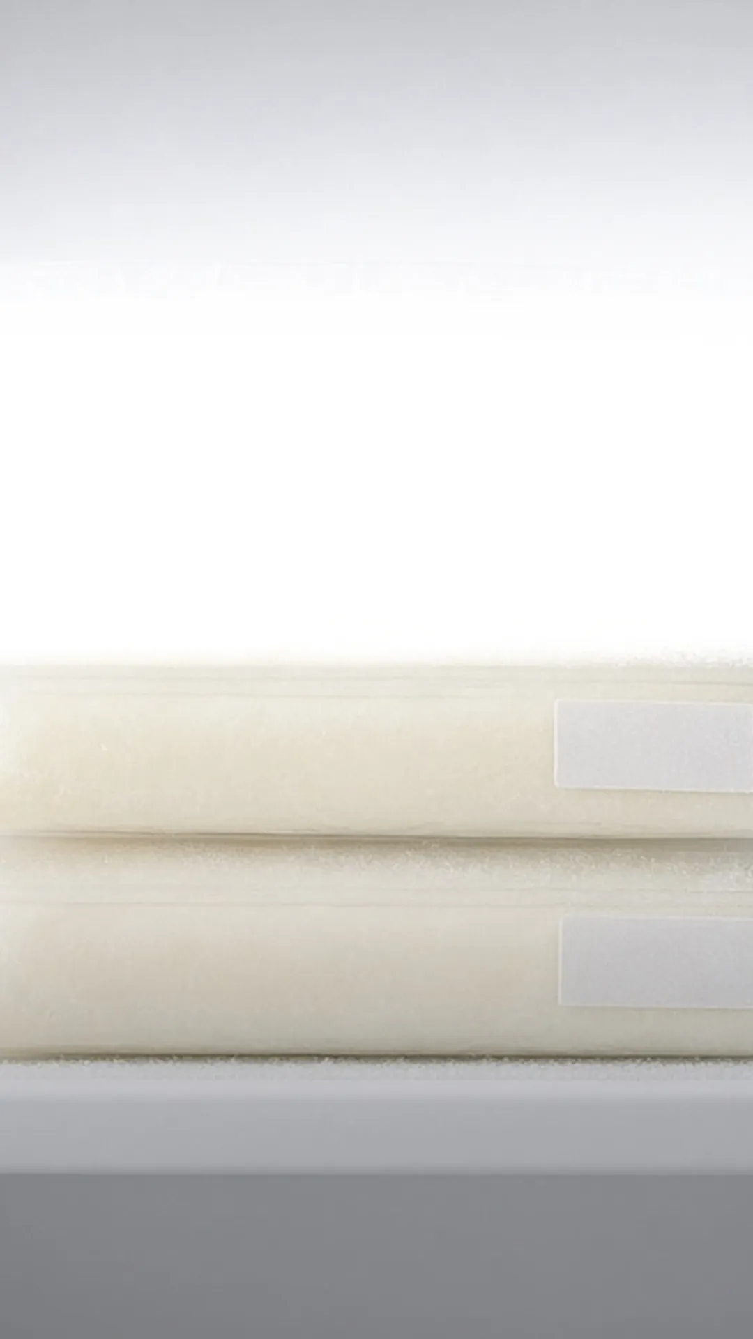 Three flat frozen milk bags with blank labels stacked on a frosted freezer shelf